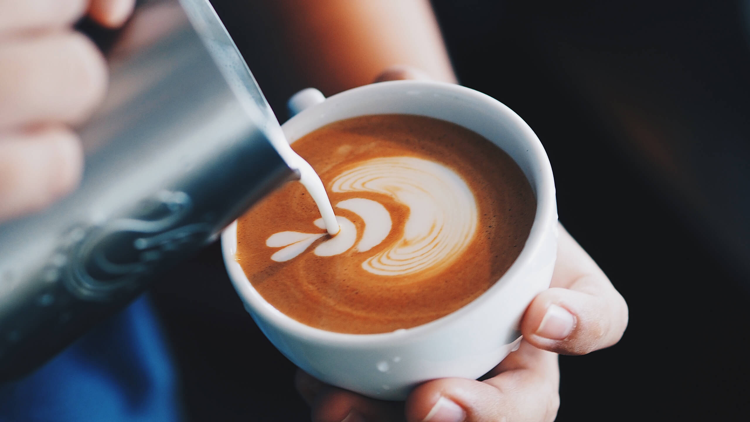 Pouring a pattern into coffee with cream